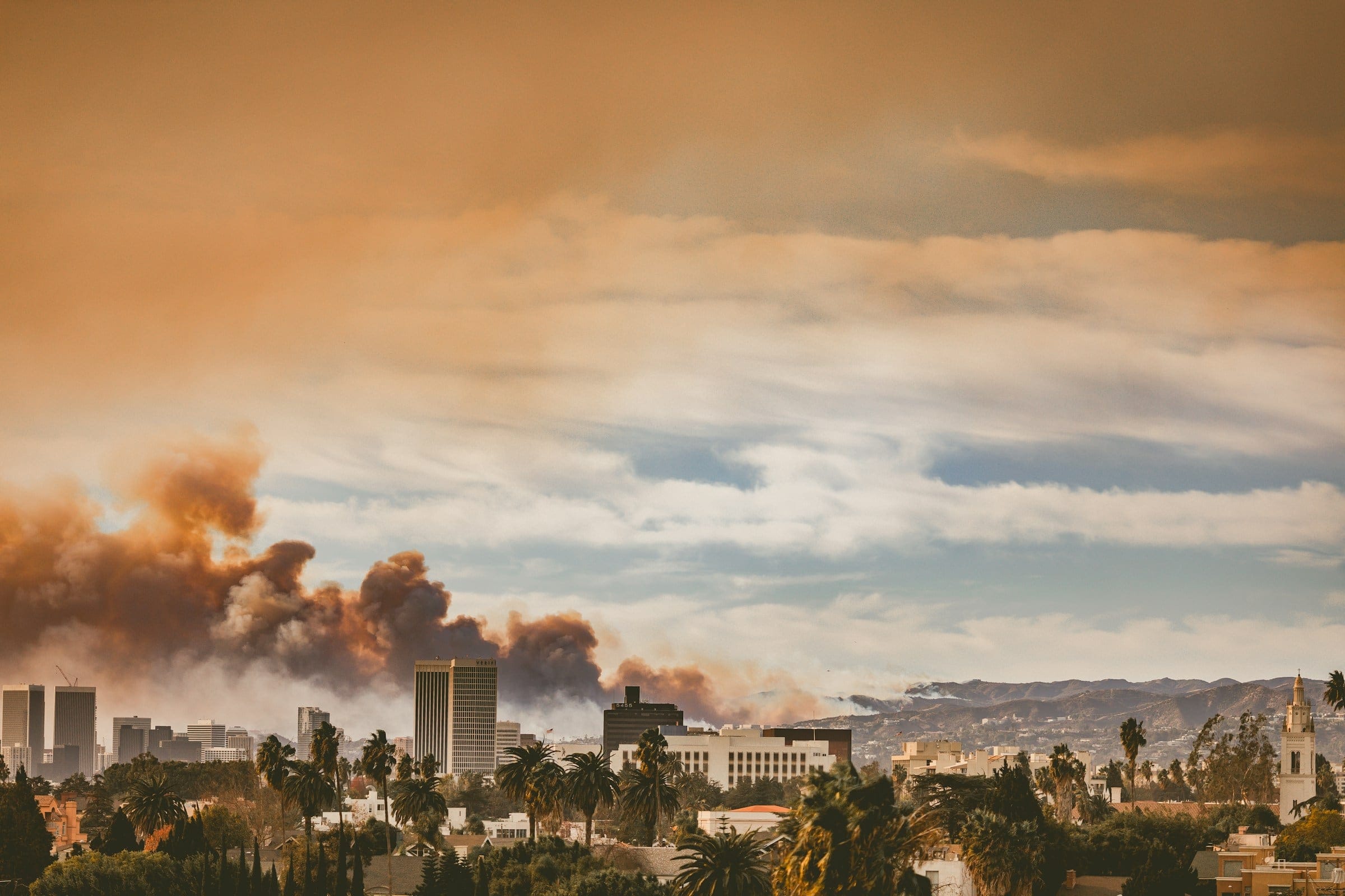 Photo by Jessica Christian showing the Eaton fire's smoke rising in the distance, viewed from Koreatown in Los Angeles